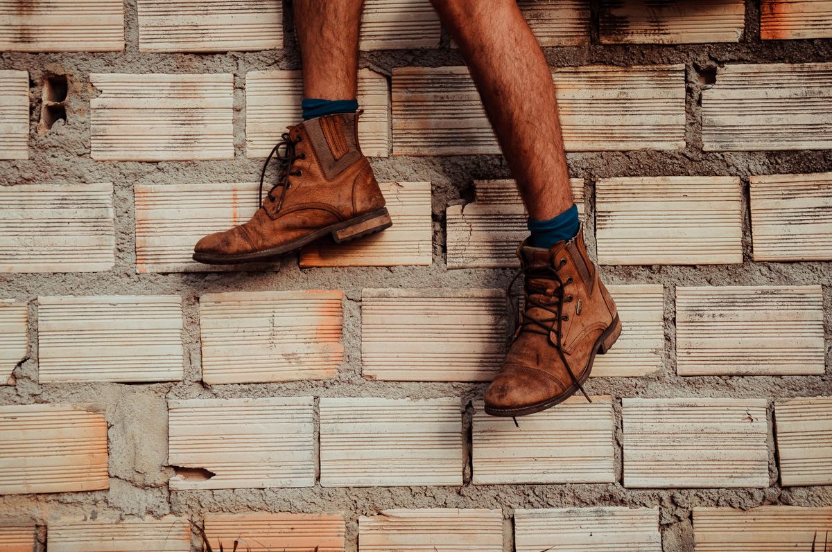 Brown lace-up leather boots worn with cuffed trousers