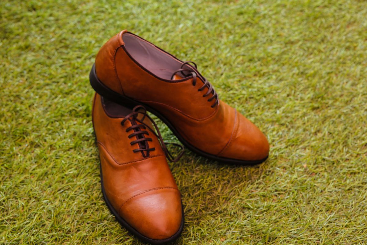 Tan cap-toe Oxford shoes on grass