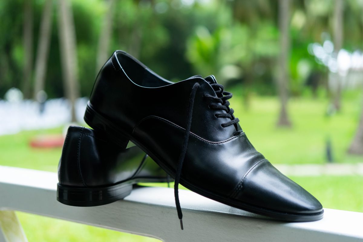 Black cap-toe dress shoes on a ledge