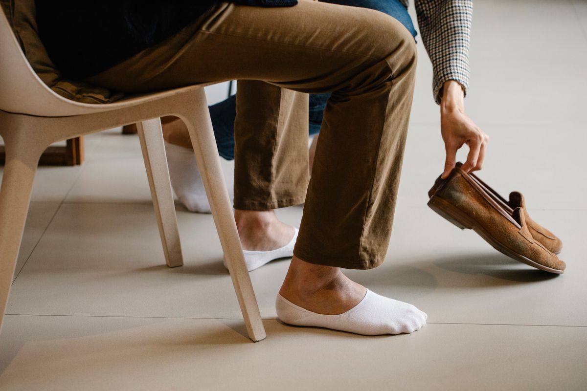 Man putting on brown loafers with chinos