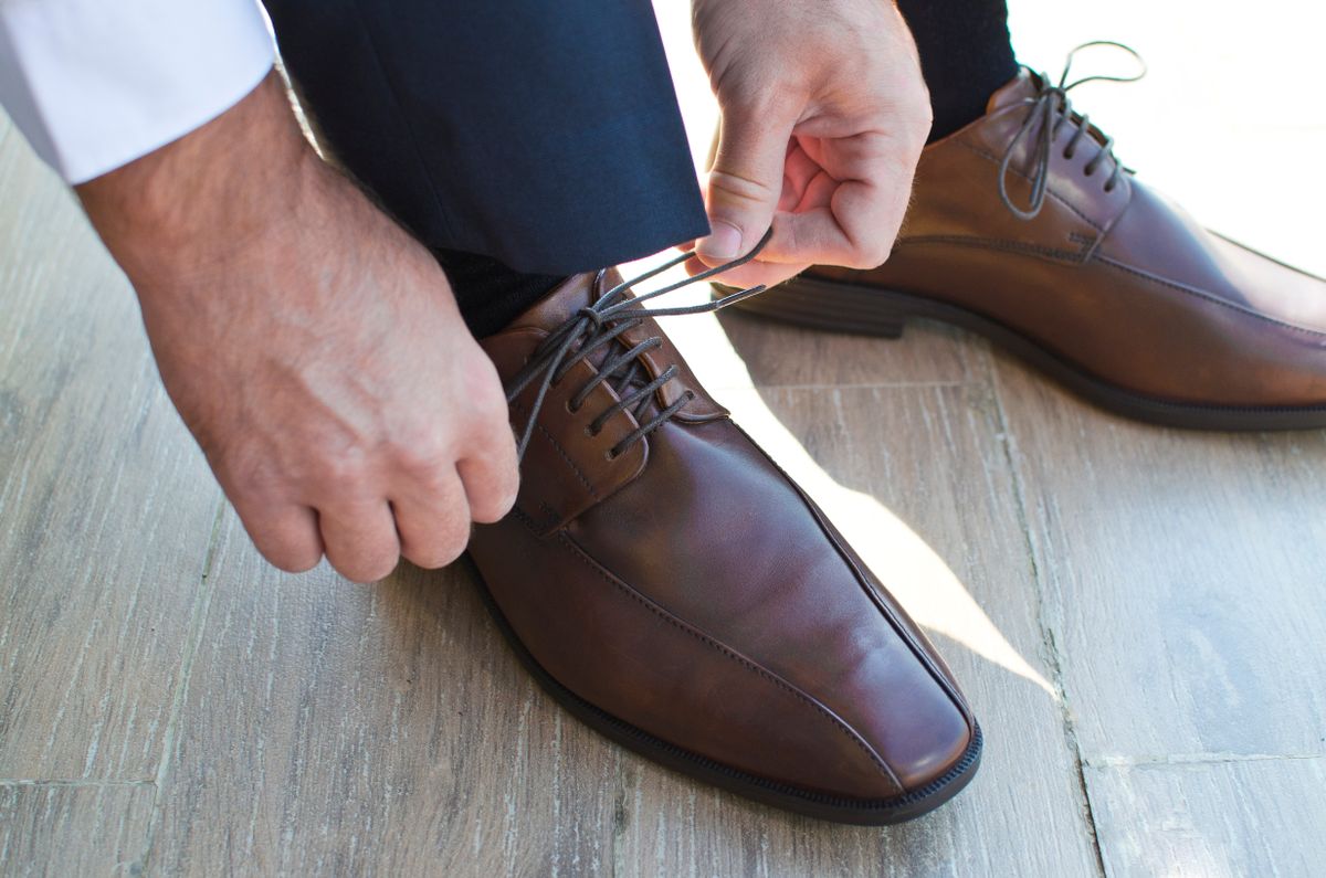 Man tying a brown leather dress shoe
