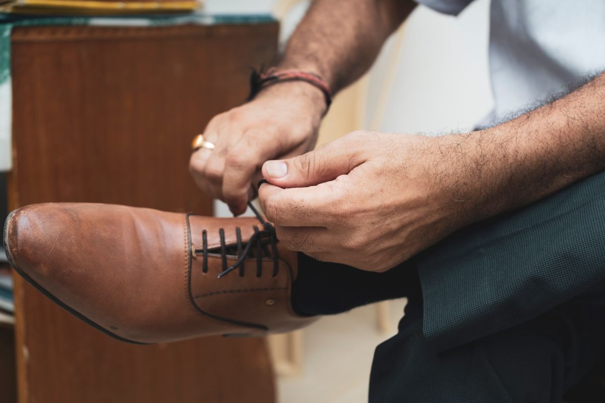 Close-up of a man tying a tan leather dress shoe