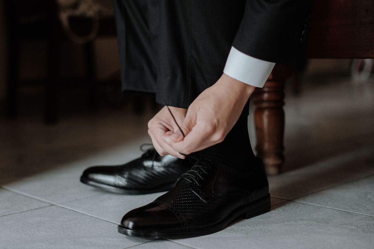 Man in a suit tying black leather dress shoes