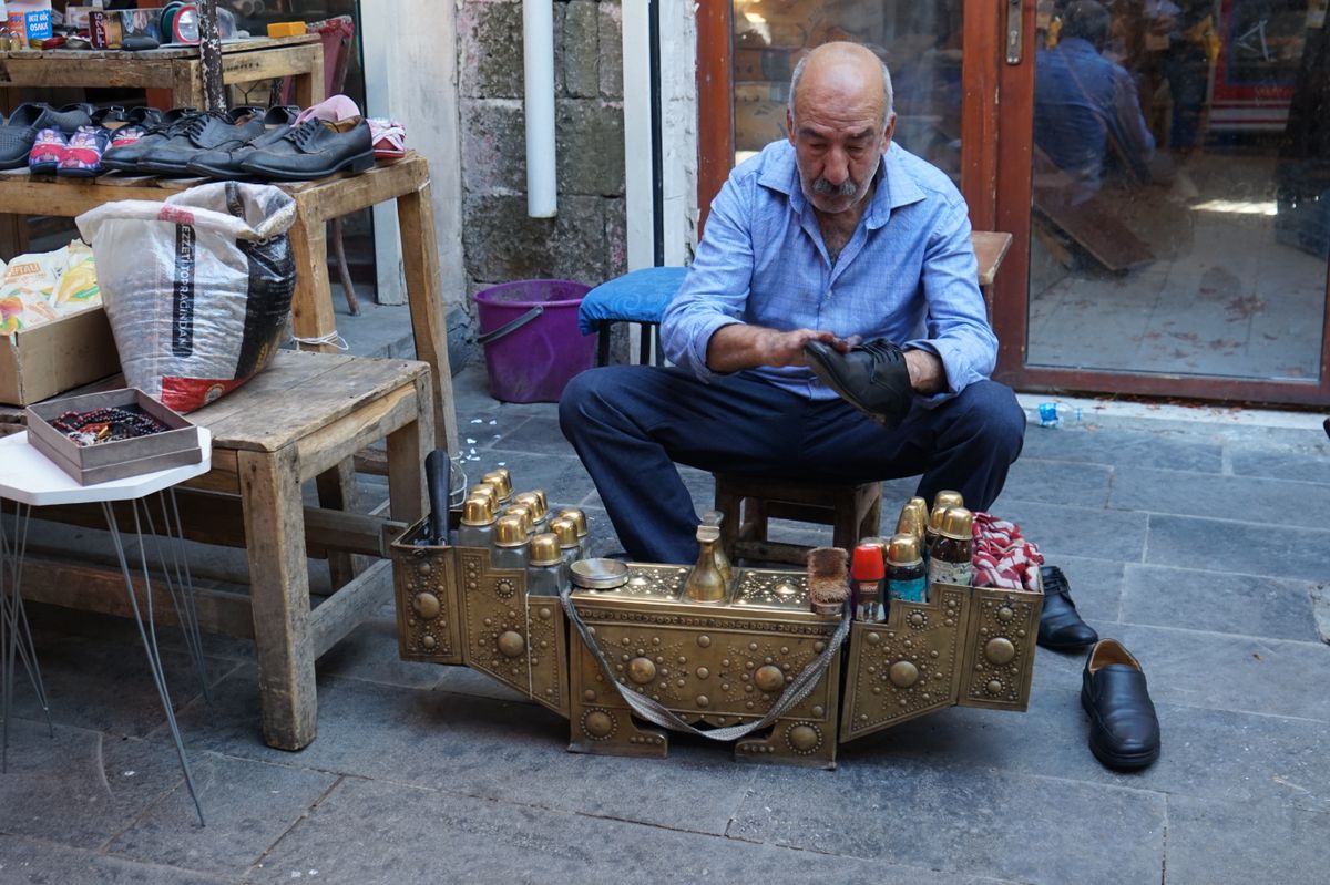Shoeshiner polishing a shoe at a street stand