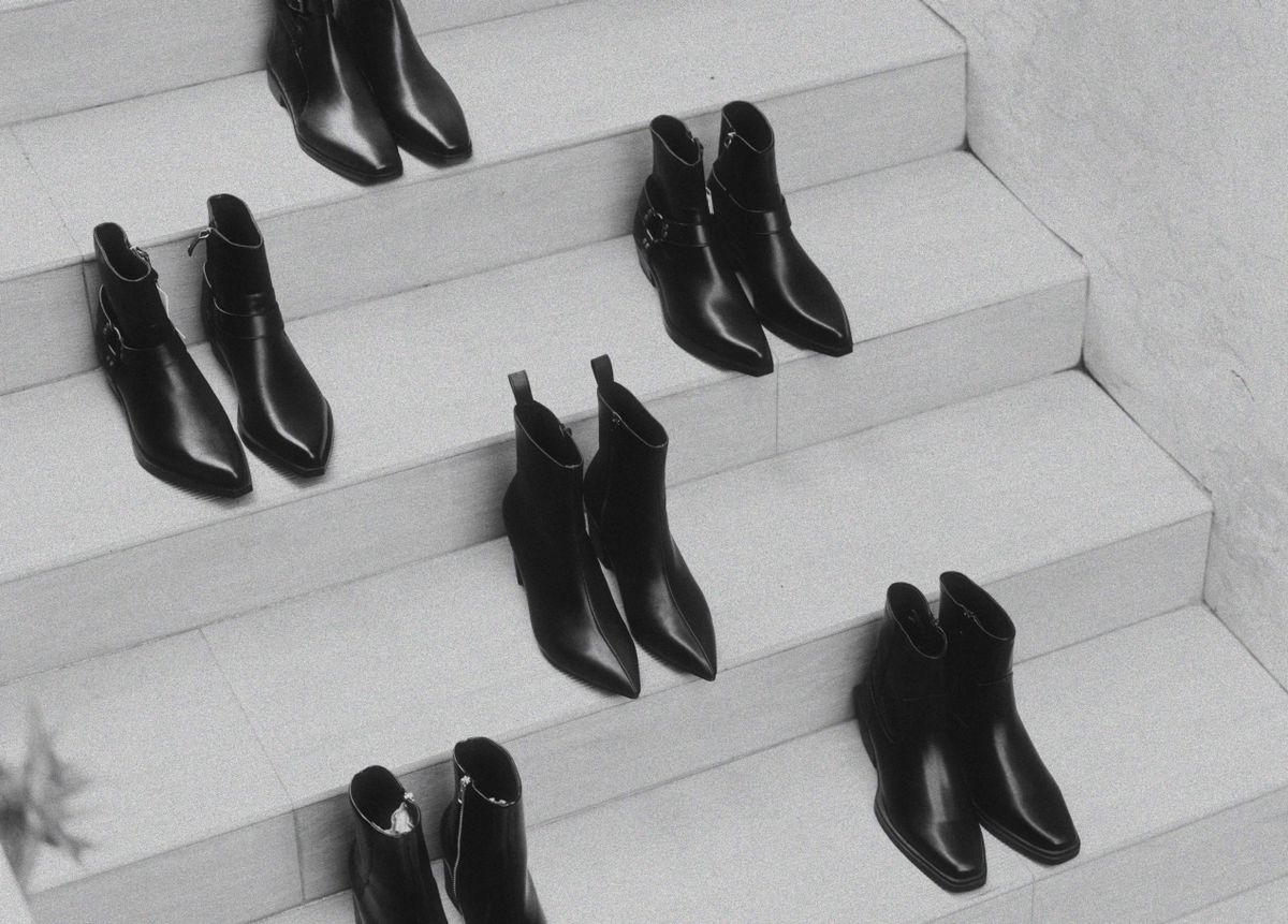 Black leather ankle boots arranged on white steps