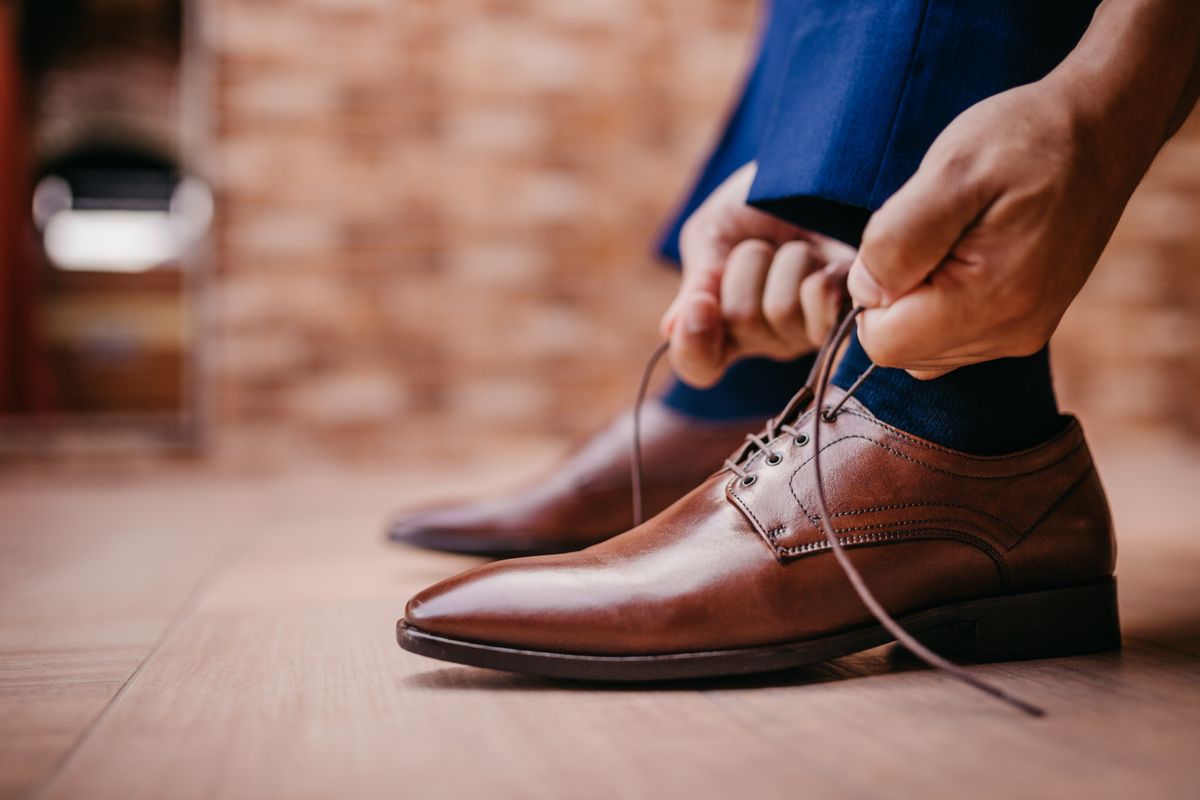 Man tying the laces of brown leather dress shoes