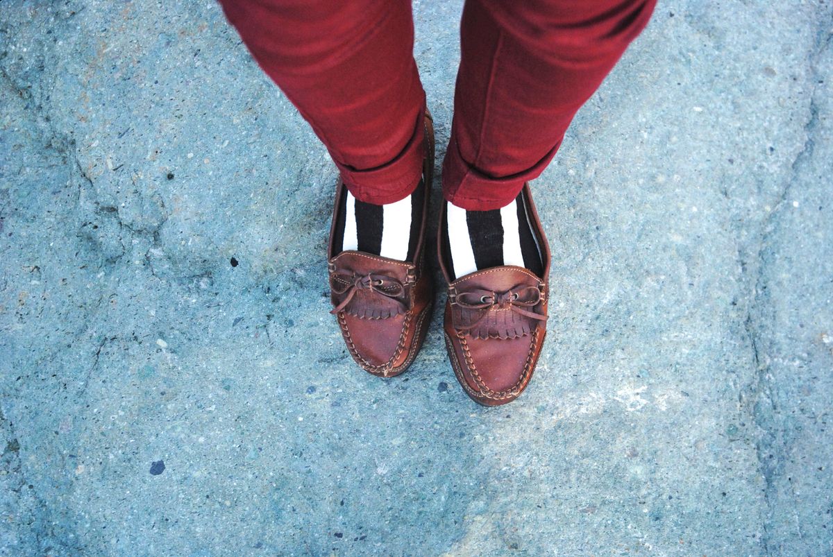 Brown tassel loafers worn with striped socks and red trousers