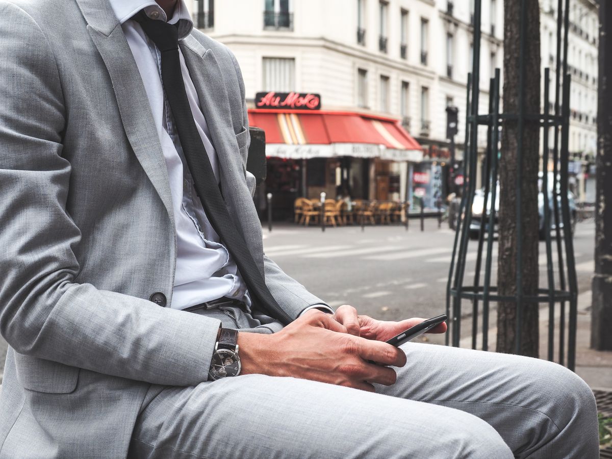 Man in a light gray suit sitting outdoors